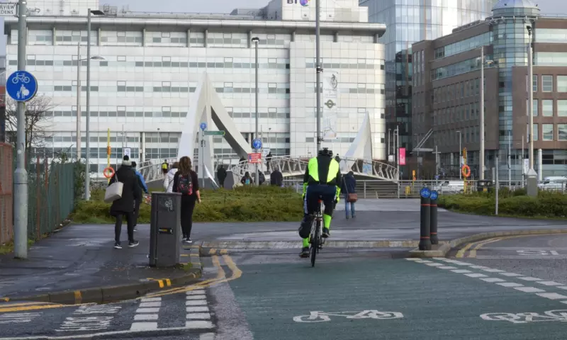 Cyclist approaching a bridge in Glasgow city centre. There are other people walking in the background.