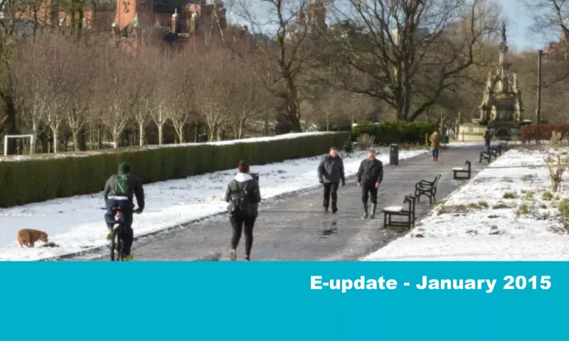People walking and cycling in a snowy Kelvingrove park.