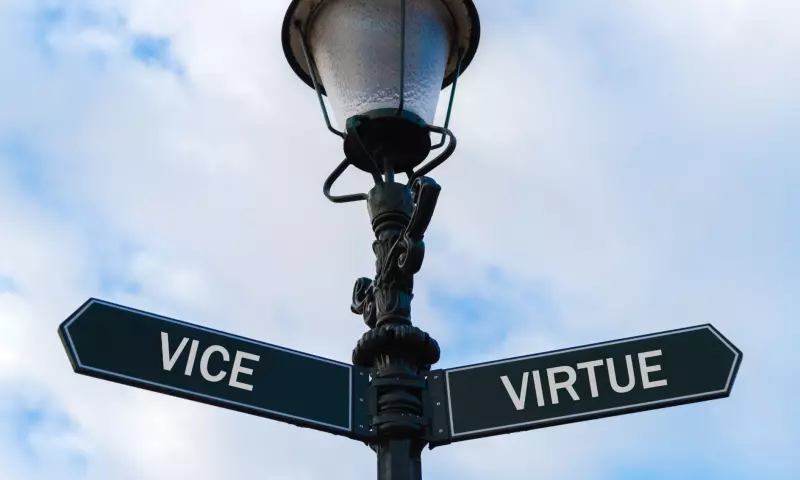Old lamp post with a sign pointing left with the word 'vice' written on, and a sign pointing right with the word 'virtue' on it.