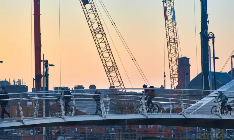 Cyclists and pedestrians crossing one of the pedestrian bridges in Glagsow, with cranes in the background.