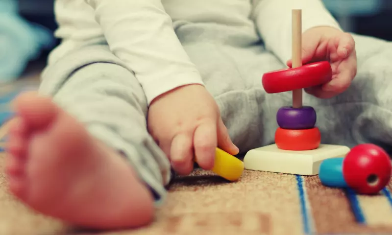 Toddler playing with wooden stacking toys.