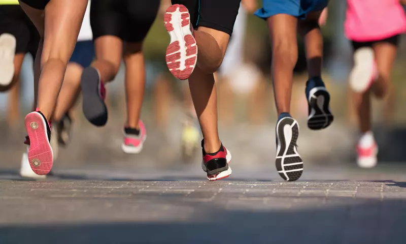 Legs of people running, wearing running attire.