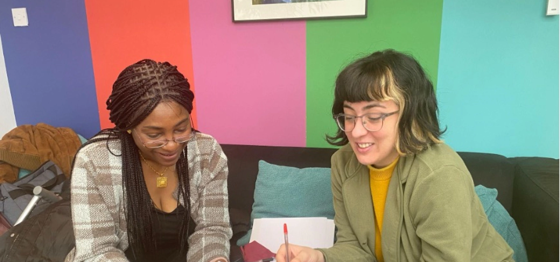 Two women sitting on a couch, talking about their research.