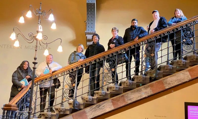 Members of the Lived Experience Panel standing on some stairs, looking at the camera.